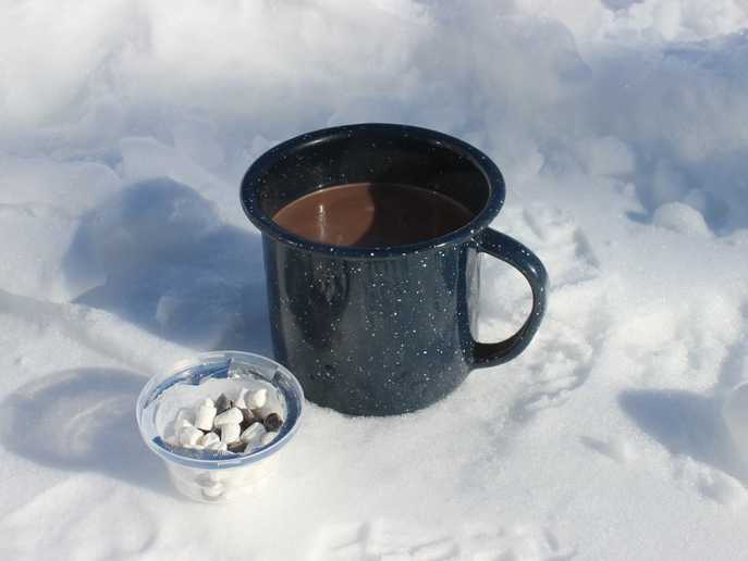 hot cup of Café Caps S’mores cocoa with open cup of marshmallow bits and chocolate chips
